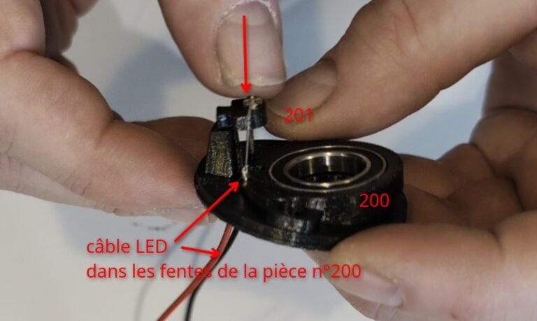 Pousser le support de LED dans son logement (n°200)Les fils doivent passer par les deux fentes dans la piece n°200.